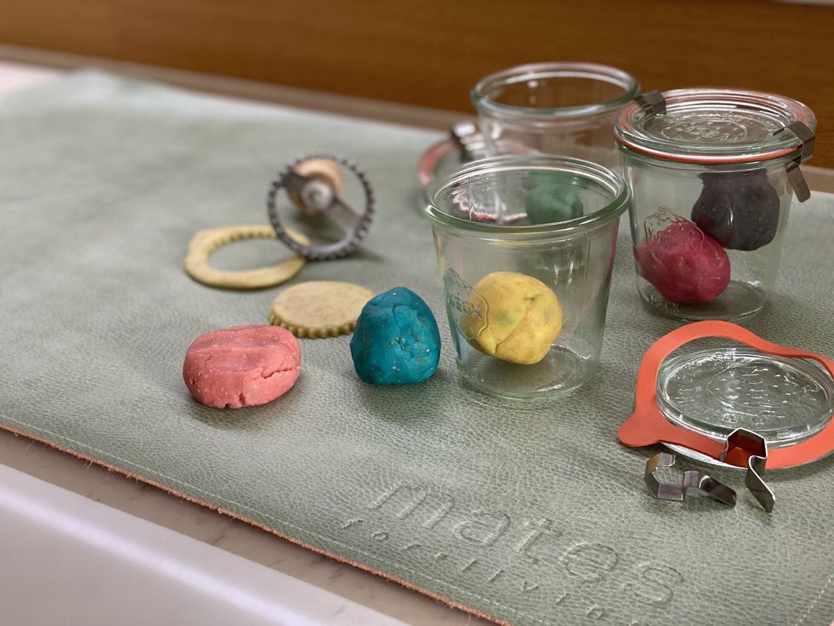 Selbstgemachte bunte Glitzerknete aus Vollkornmehl in Einmachgläsern und als Kugeln auf einer grünen mates for living Unterlage