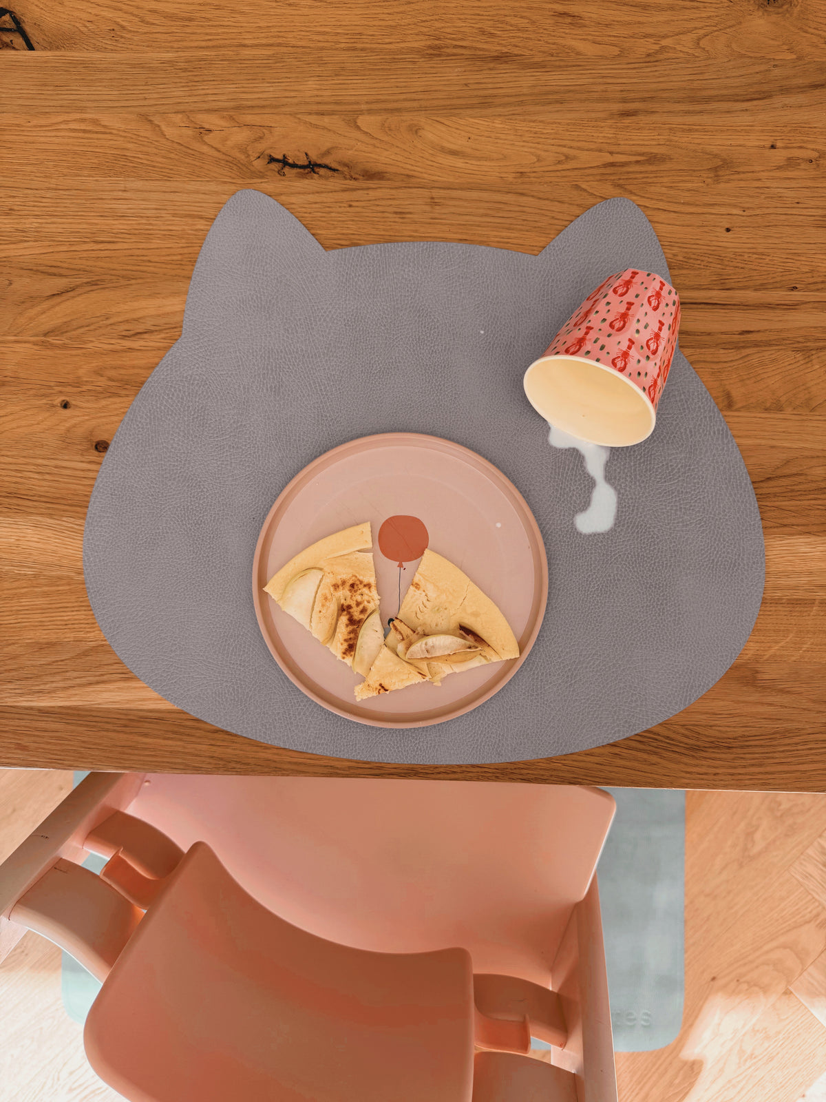 Abwaschbares Kinder-Tischset Katze in Cloudy Gray im Soft LederLook mit verschütteter Milch auf dem Holztisch